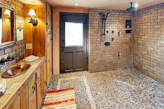 Luxury bath with pebble-stone flooring, multi-head shower, and hammered-copper sink.