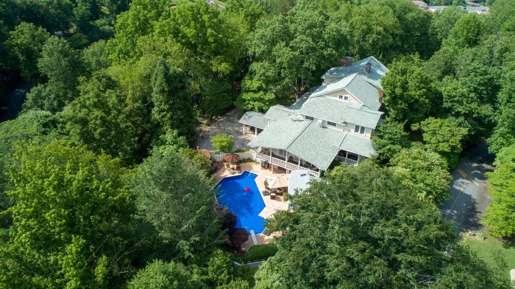 Aerial view of historic luxury home with dark swimming pool liner color.