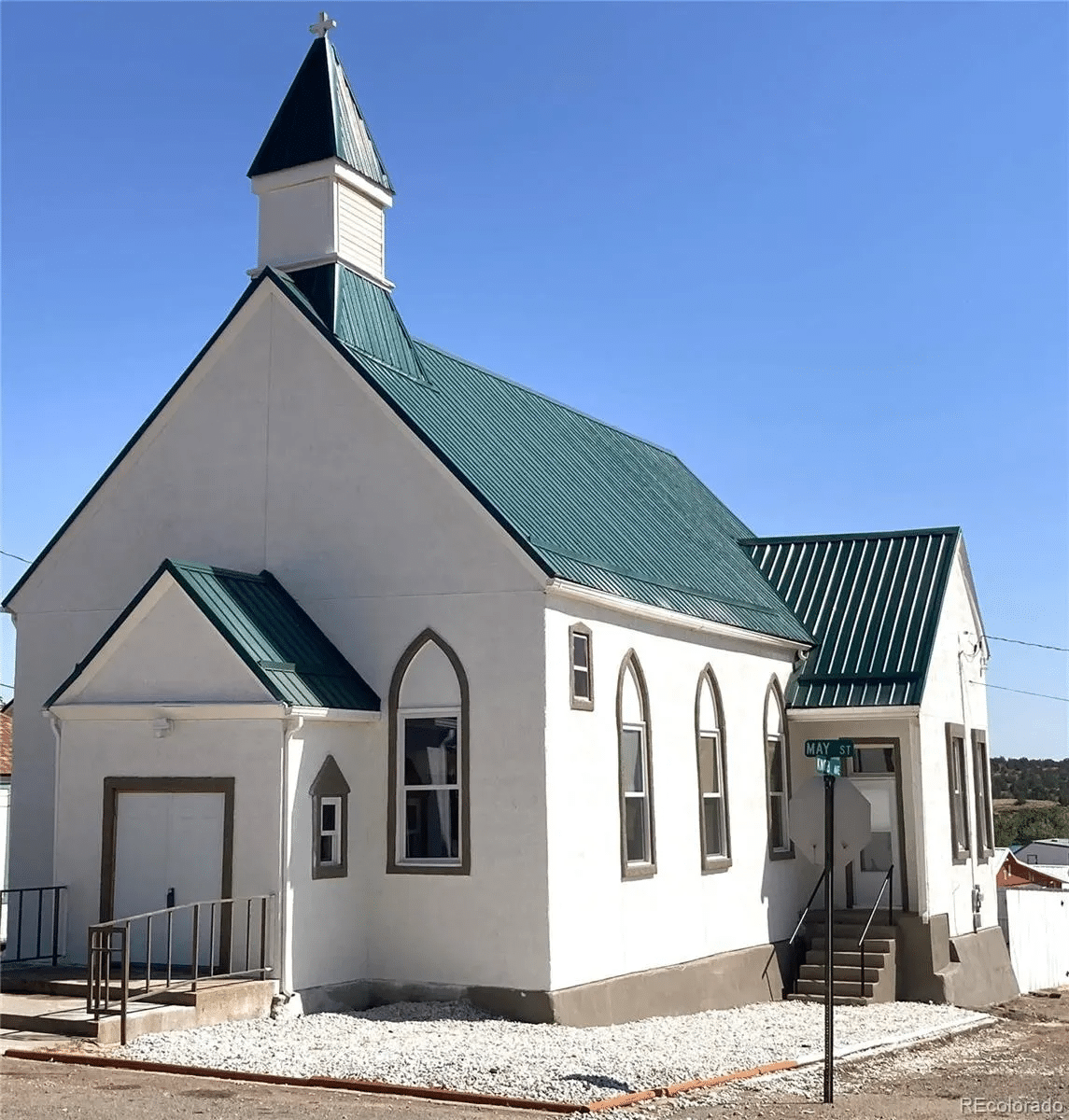 Exterior view of a historic church with a green metal roof, now transformed into a home.