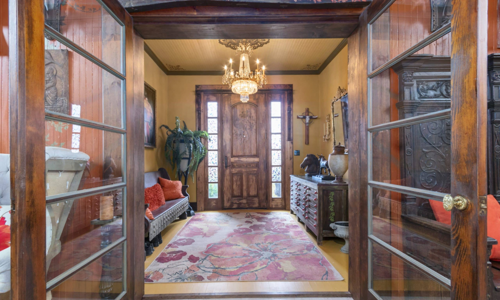 An image of an ornate entryway with a chandelier and rich wooden details.