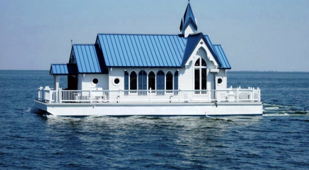 The floating chapel with a blue roof and white exterior, now serving as a luxury floating home.