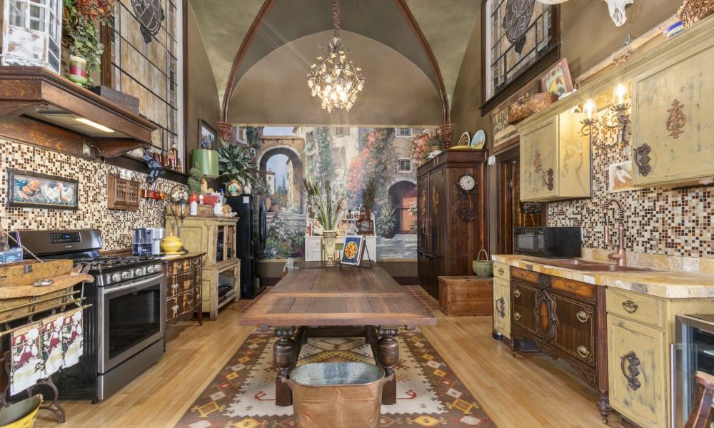 A detailed view of a kitchen with vaulted ceilings, rustic cabinetry, and a decorative mural.